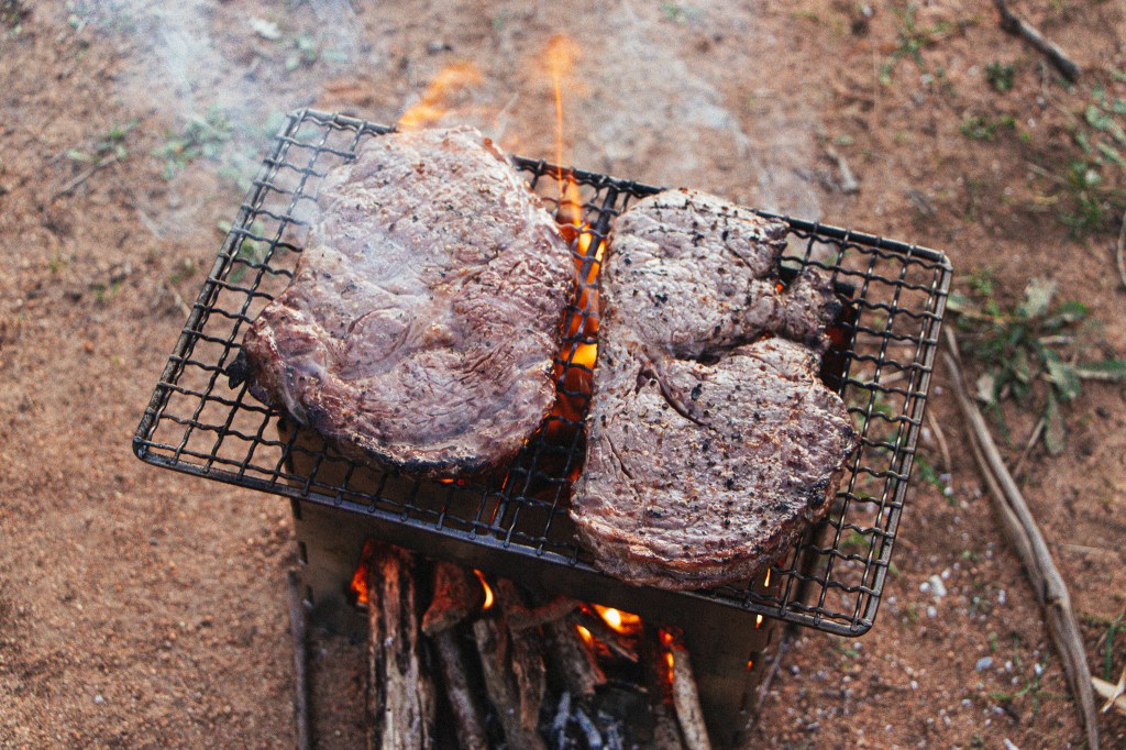 Cooking steaks on the Alton Grill using a wood fire stove